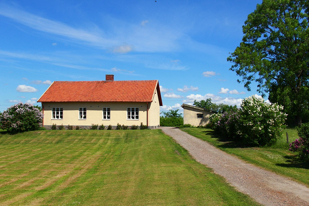 Gult bostadshus med gräsmatta och grusväg