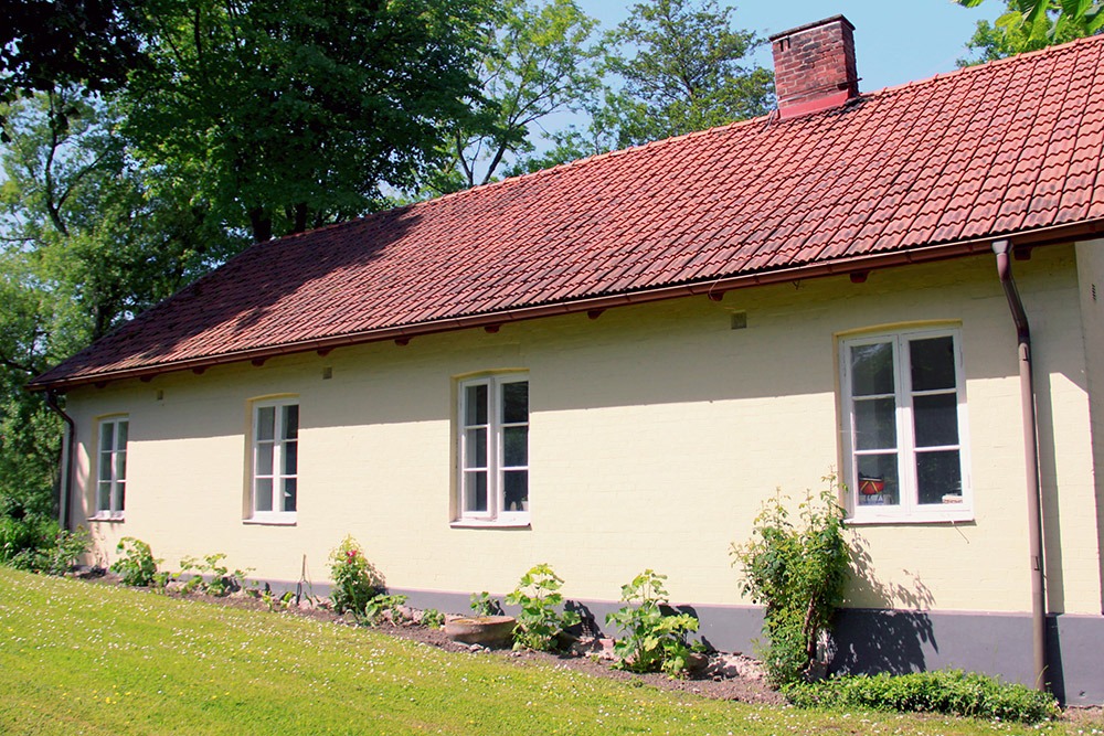 Gult bostadshus med plantering längs väggen